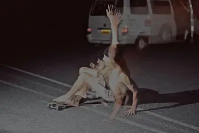 Multiple-exposure portrait of a woman posing on a skateboard beside a camper van at night