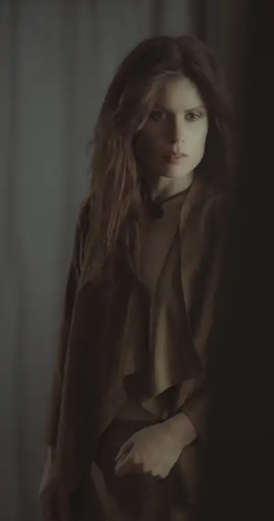 Portrait of a woman standing in soft window light against a dark background