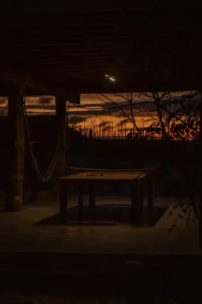 Orange sunset seen through the open side of a dark wooden room