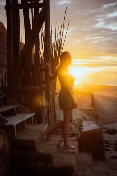 Woman silhouetted in a doorway with the setting sun behind her