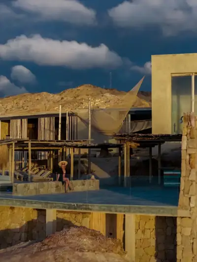 Pool reflecting a modern building beneath mountains and dark clouds