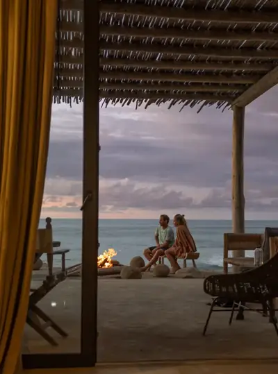 Two people sitting on a terrace overlooking the ocean at dusk