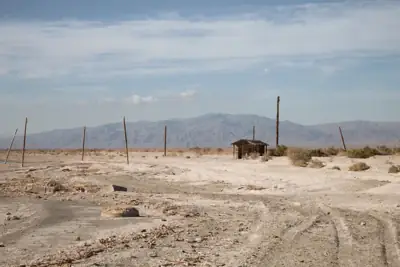 Four-wheel-drive vehicle crossing a dry open landscape beneath distant mountains
